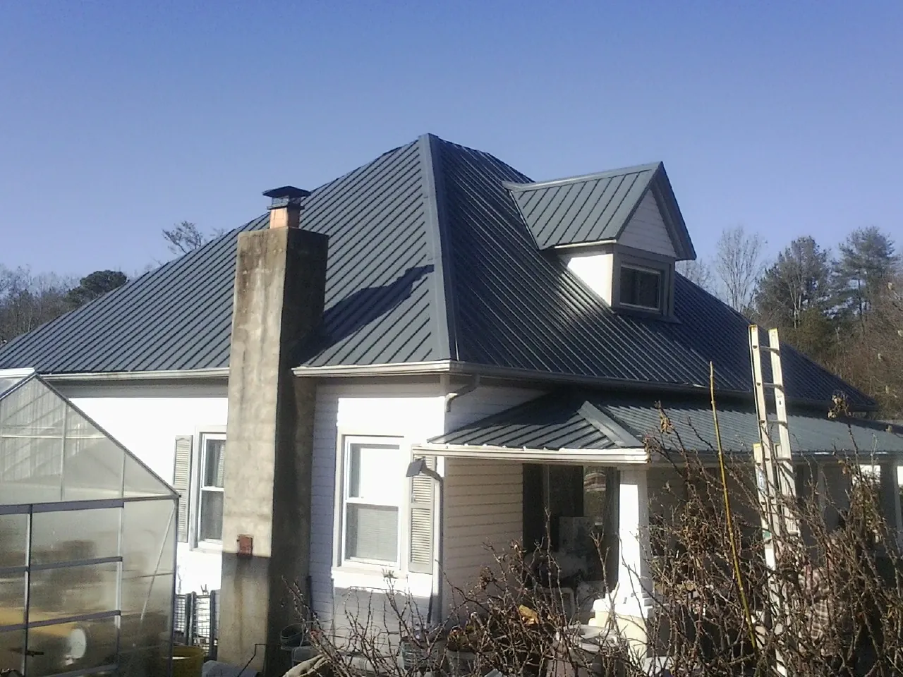 Dark blue standing seam metal roof on a white farmhouse with dormer — Slate & Tile Roof Repair by Roofing Brothers in Burlington